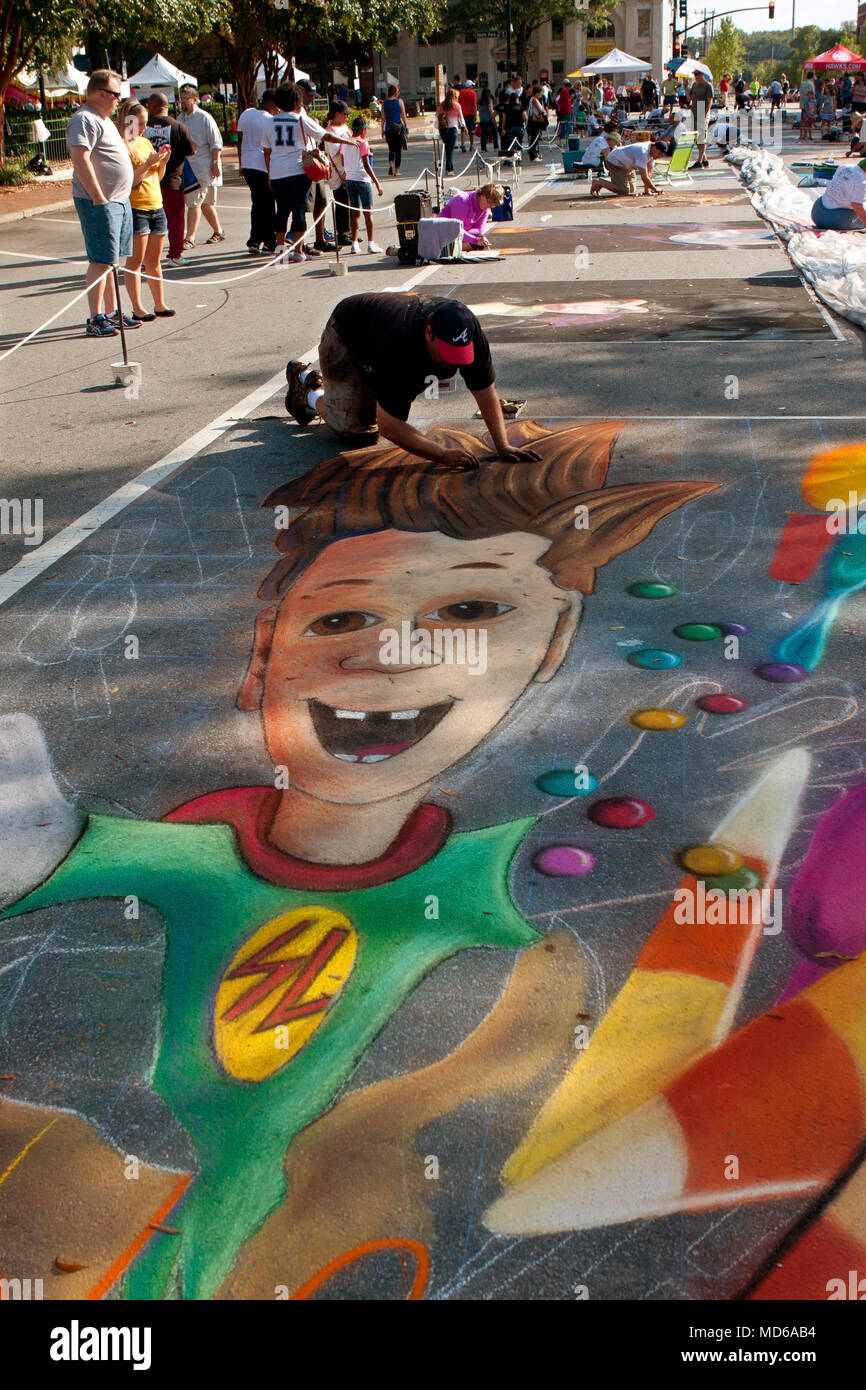 A chalk artist draws an elaborate Halloween scene on a downtown street as part of the Marietta