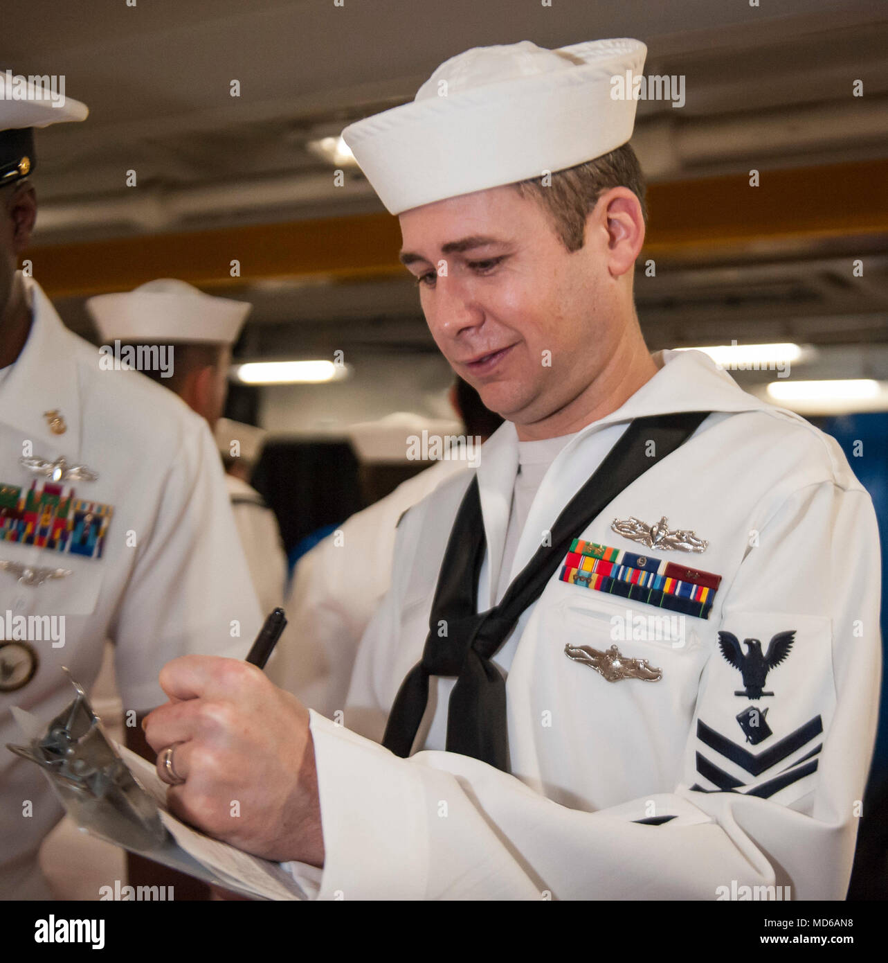 180326-N-WX604-0070 ATLANTIC OCEAN (March 26, 2018) Personnel Specialist 1st Class William E. Curtis, from Houston, Texas, annotates uniform discrepancies during a service dress white uniform inspection in the fo'c'sle aboard the aircraft carrier USS George H.W. Bush (CVN 77). The ship is underway conducting sustainment exercises to maintain carrier readiness. (U.S. Navy photo by Mass Communication Specialist 2nd Class Joseph E. Montemarano) Stock Photo