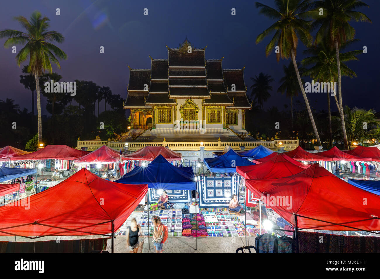 Night market and lit Haw Pha Bang temple, also known as Royal or Palace Chapel, next to the Royal Palace in Luang Prabang, Laos, at dusk. Stock Photo