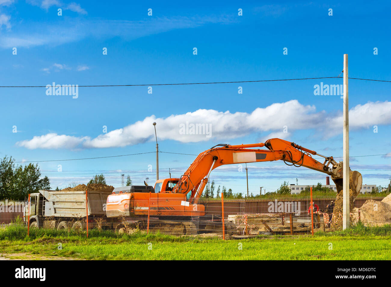 Excavator bucket loads heavy truck with ground on construction of