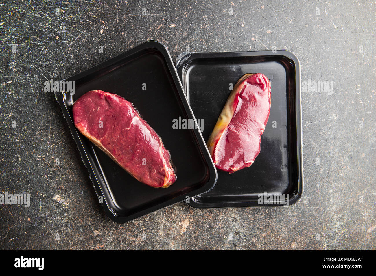 Fresh raw beef meat in foil box on old kitchen table. Stock Photo