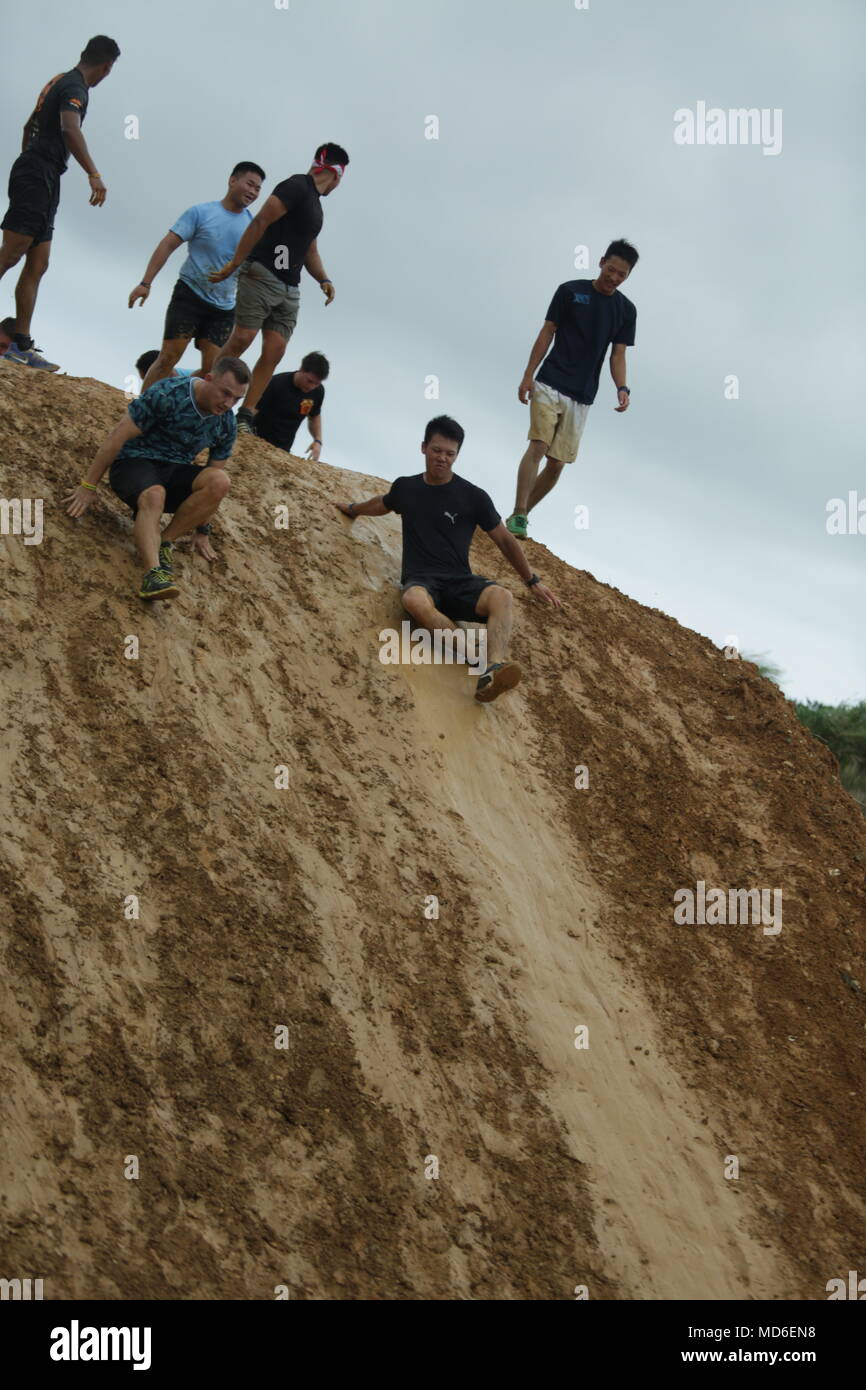 CAMP HANSEN, OKINAWA, Japan – Competitors slide down a mud hill during the 2018 Camp Hansen World Famous Mud Run April 15 aboard Camp Hansen. The event had a both a fun run and competition 5-kilometer and 10km race for teams and individual runners. The event was open island-wide, allowing all ages and fitness levels to complete to challenge. (U.S. Marine Corps photo by Pfc. Kelcey Seymour) Stock Photo