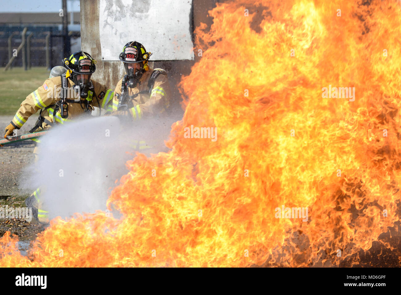Daniel Manning and Stephen Cooper, 100th Civil Engineer Squadron firefighters, extinguish an aircraft fire as part of annual proficiency skill training for firefighters at their training burn pit on RAF Mildenhall, England, March 21, 2018. These exercises provide training and keep fire team members prepared with the techniques needed to control an aircraft fire. (U.S. Air Force photo by Tech. Sgt. Emerson Nuñez) Stock Photo