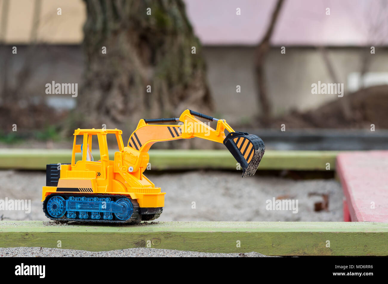 Plastic toy excavator in the sand. Children's toy. Childhood memories