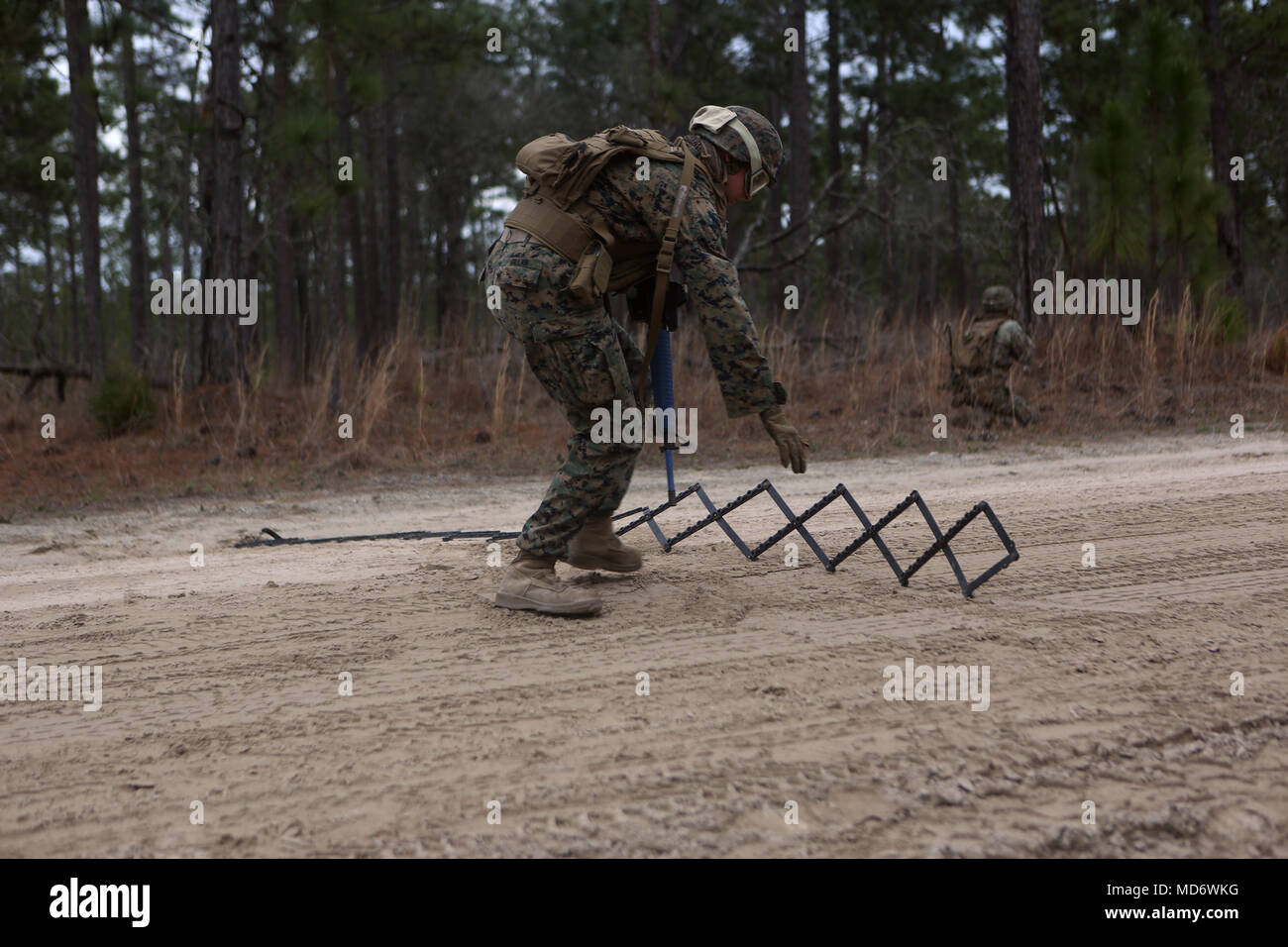 U.S. Marine Lance Cpl. Jared Gillan, a military policeman with 2nd Law Enforcement Battalion, 2nd Marine Information Group, lays down a spike strip during a close quarter’s tactics enabler’s course at Camp Lejeune, N.C., March 27, 2018. The course provided Marines the opportunity to improve fire and movement tactics as a security platoon element. Marines participated in the training in preparation for their upcoming deployment with 22nd Marine Expeditionary Unit. (U.S. Marine Corps Photo by Pfc. Heather Atherton) Stock Photo
