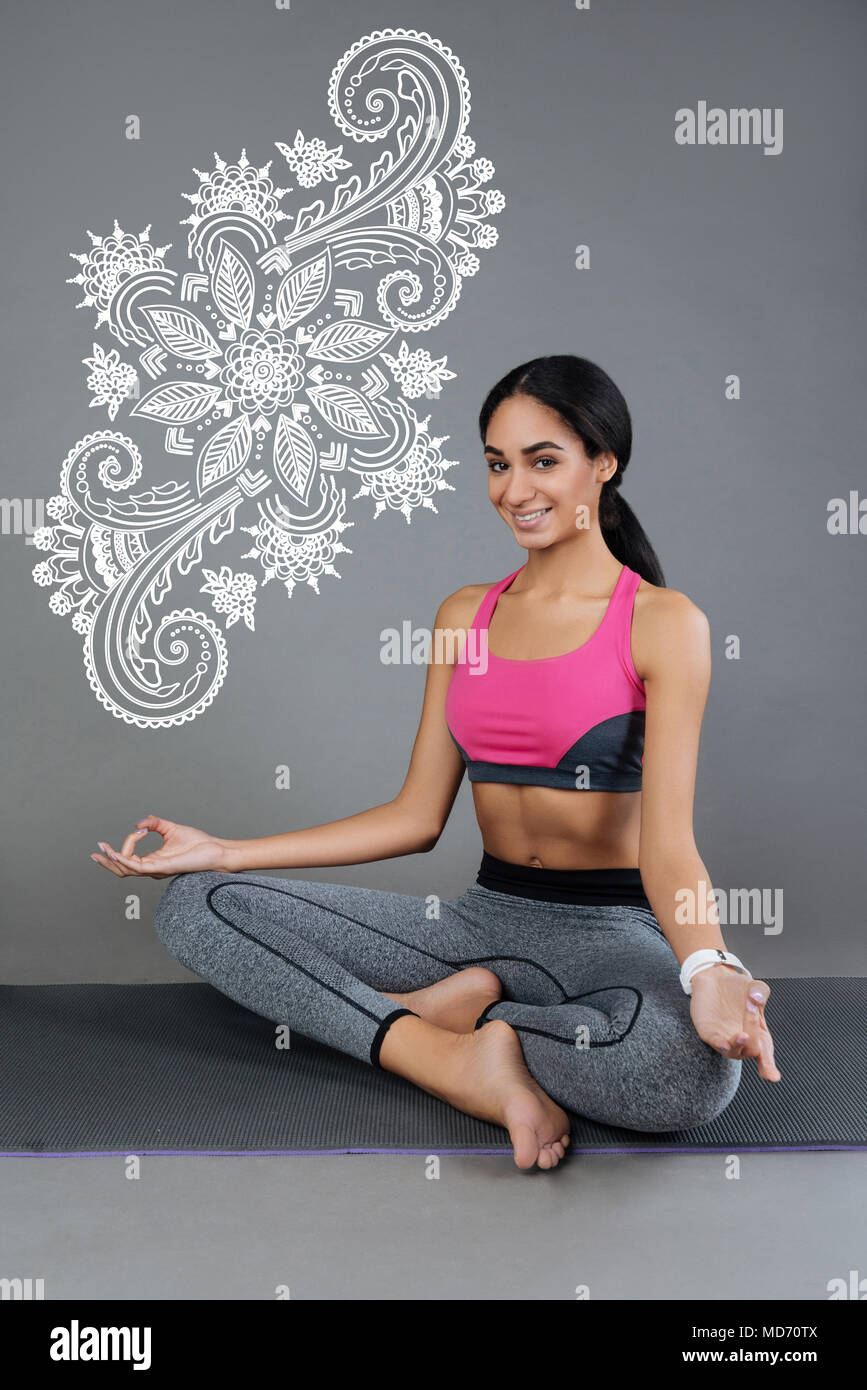 Beautiful girl sitting on a yoga mat and smiling Stock Photo - Alamy