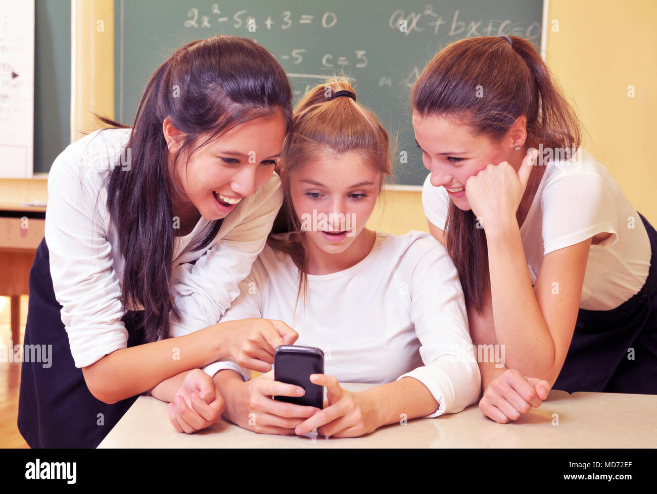 Three happy high school girls have fun with their cell phone Stock Photo
