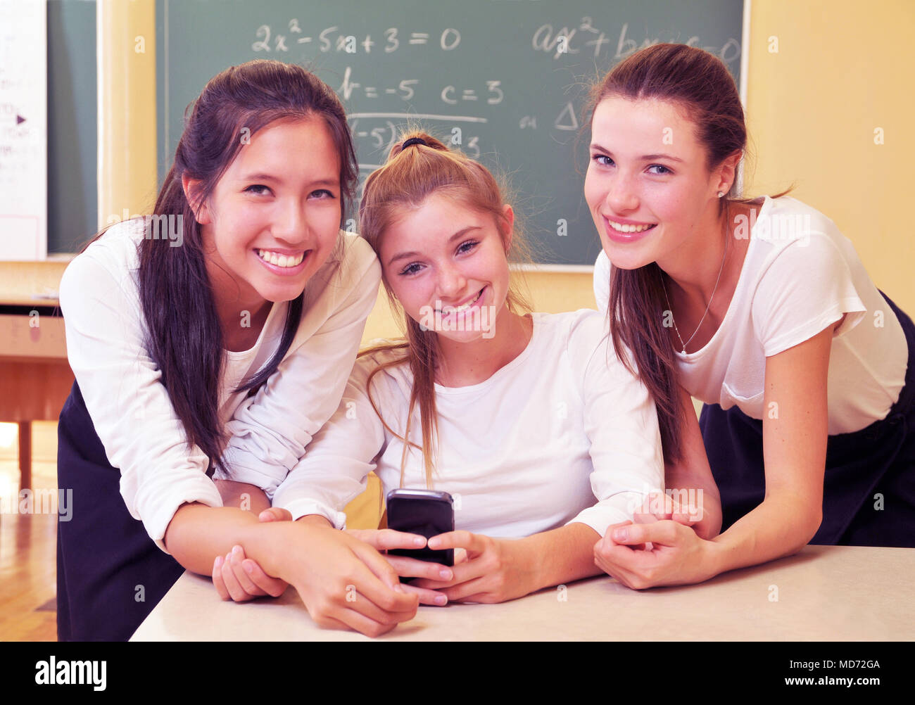 Three happy high school girls have fun with their cell phone Stock Photo