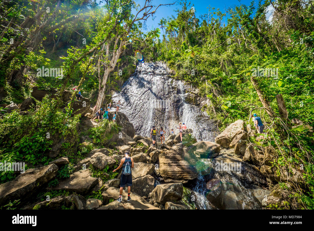 Six months after Hurricane Maria, only a small portion of El Yunque National Forest, Puerto Rico, is available for enjoyment. Here, tourists enjoy climbing La Coca Waterfall. Stock Photo