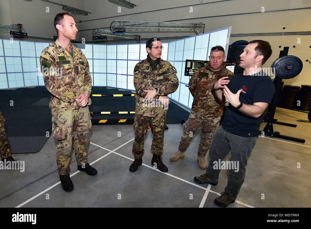 From Right, Michael Kennicker, instructor Gunfighter Gym ,shows at Sgt. Maj. Gaetano Massimo Giordano Italian Army, Lt. Col. Giuseppe Galloro Chief Training Office of the 85th Reggimento Addestramento Volontari “Verona” and Capt. Daniele Trenteni of the Regiment “Savoia Cavalleria” Folgore Brigade Grosseto  , simulated shooting drill at the Gunfighter Gym , Caserma Del Din, Vicenza, Italy, March 28, 2018. Italian Soldiers use U.S. Army RTSD South equipment to enhance bilateral relations and to expand levels of cooperation and the capacity of the personnel involved in joint operations. (U.S. Ar Stock Photo