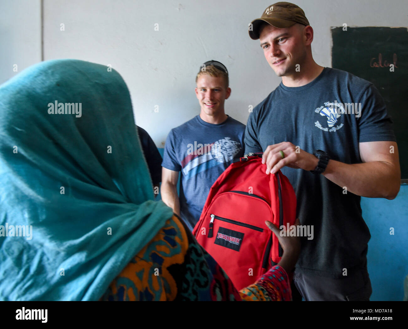 U.S. Army 1st Lt. Aidan Dietz, with Animal Company, 3rd Battalion, 141st Infantry Regiment, assigned to Combined Joint Task Force - Horn of Africa (CJTF-HOA), hands a backpack filled with school supplies a Somali child in Ali Oune, Djibouti, March 28, 2018. CJTF-HOA service members donated more than $400 of school supplies and sandals to Somali refugee students in Djibouti.  (U.S. Air Force photo by Staff Sgt. Timothy Moore) Stock Photo