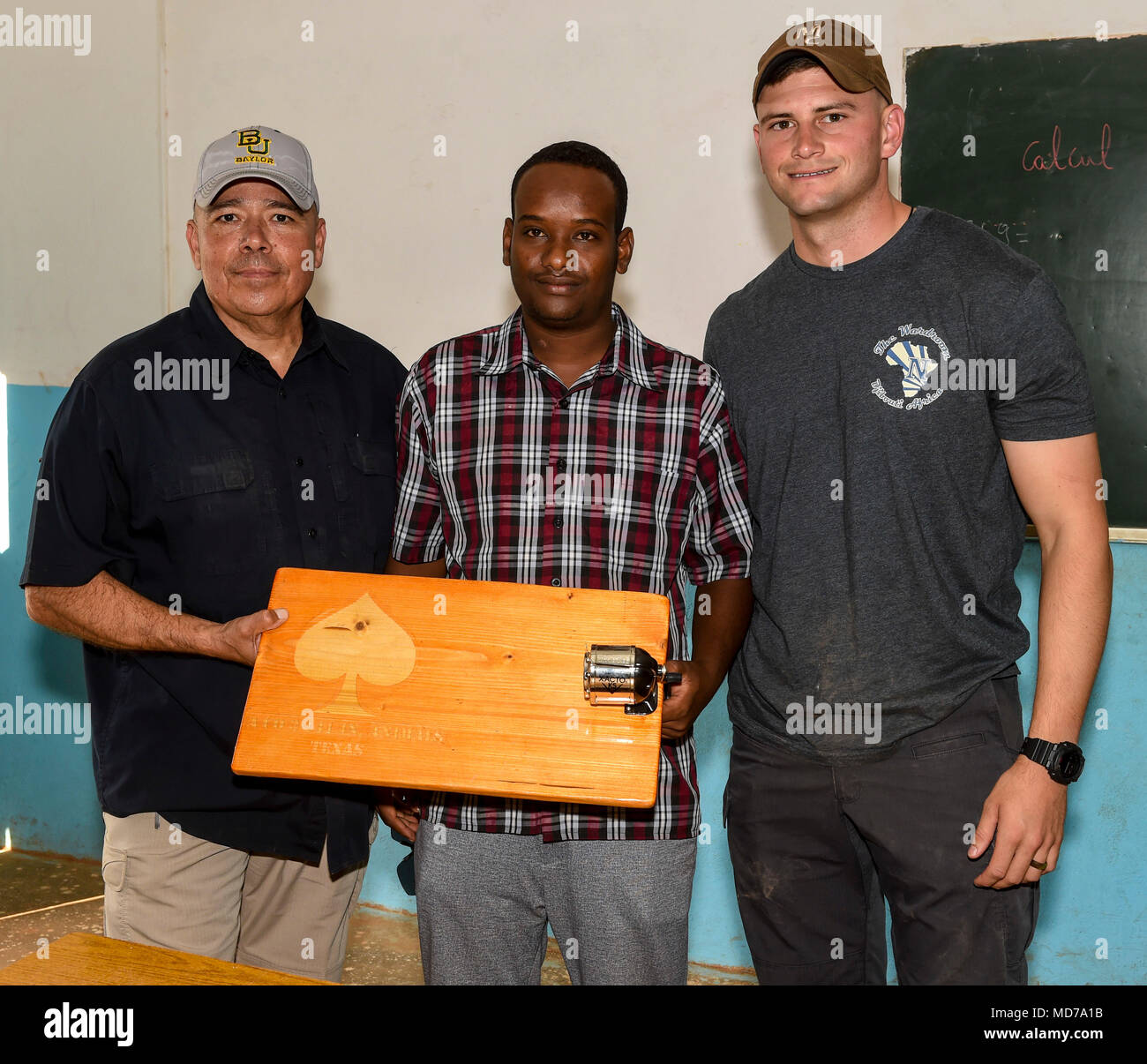 U.S. Army Sgt. 1st Class Juan Vela, left, and 1st Lt. Aidan Dietz, right, both with Animal Company, 3rd Battalion, 141st Infantry Regiment, assigned to Combined Joint Task Force - Horn of Africa (CJTF-HOA), present a portable manual pencil sharpener to Amin Houssein, teacher, in Ali Oune, Djibouti, March 28, 2018. CJTF-HOA service members donated more than $400 of school supplies and sandals to Somali refugee students in Djibouti. (U.S. Air Force photo by Staff Sgt. Timothy Moore) Stock Photo