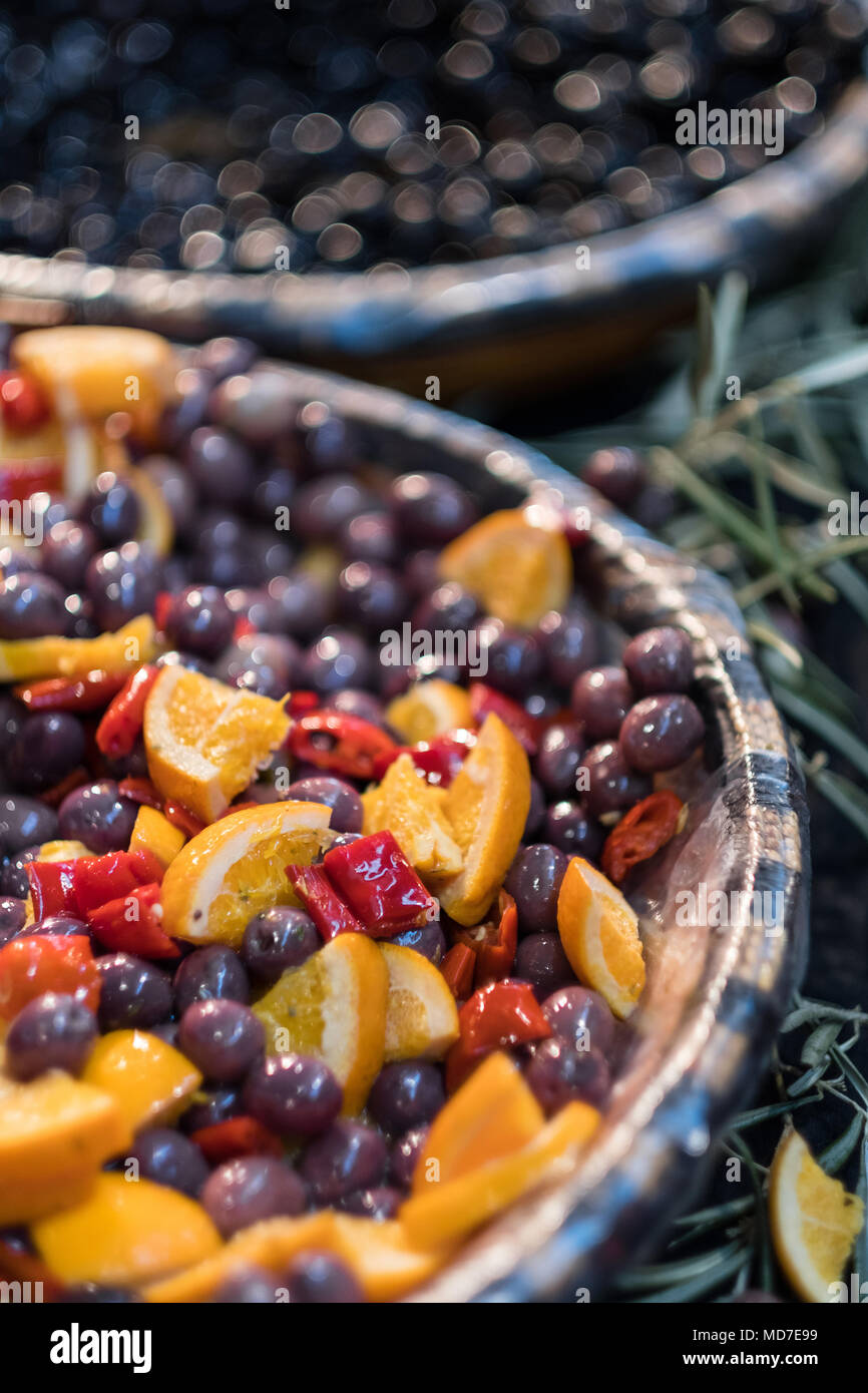 red kalamata olives marinated in oil decorated with oranges and peppers on display at market Stock Photo