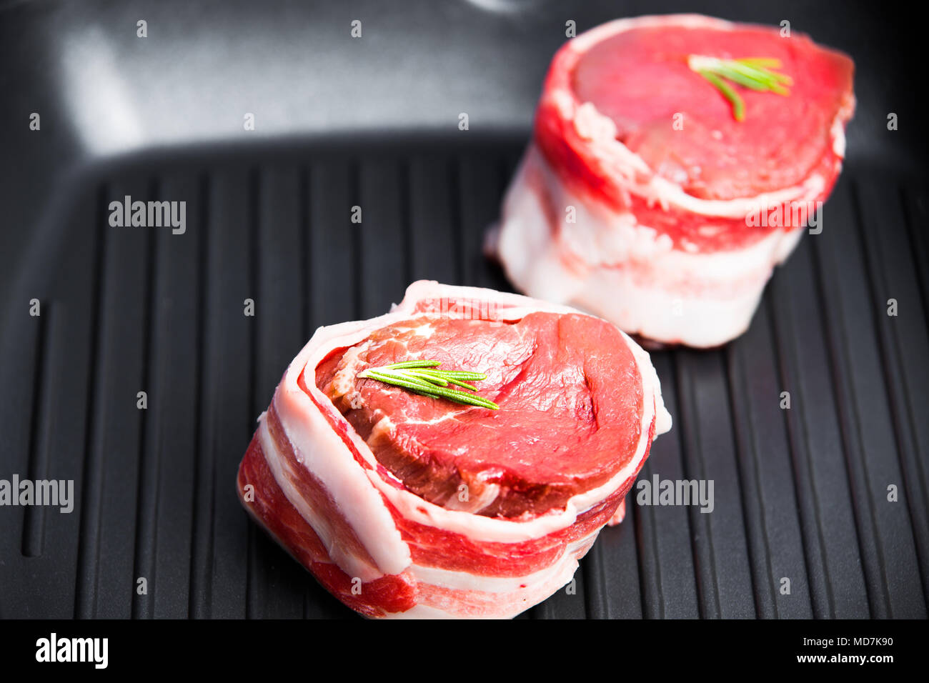 Raw steak fillet mignon in a grilled pan close-up with a sprig of rosemary. Theme of tasty and healthy food. Stock Photo