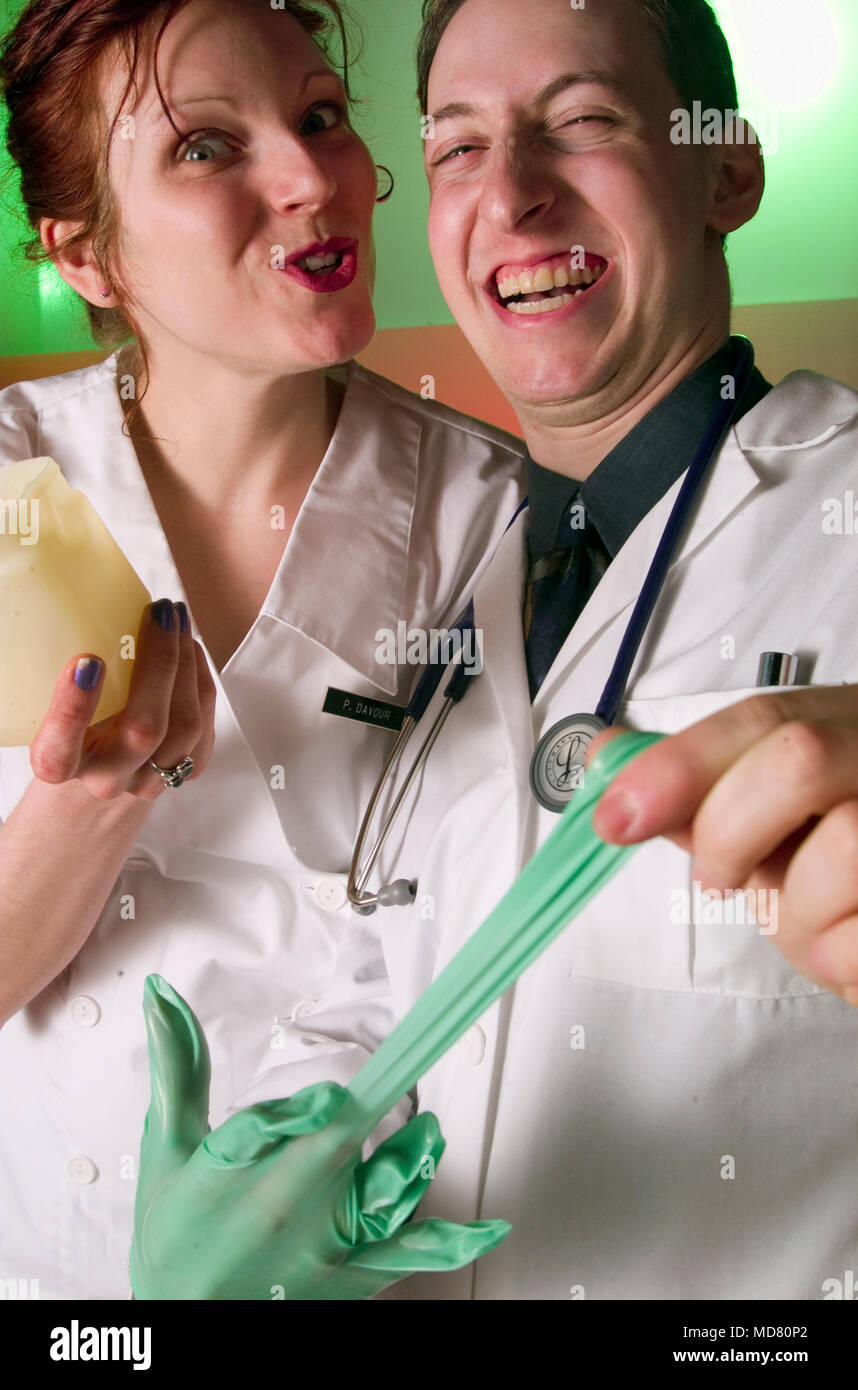 A humorous photo of a doctor and a nurse getting ready for a delicate medical exam. The doctor is donning rubber gloves and the nurse is holding a con Stock Photo