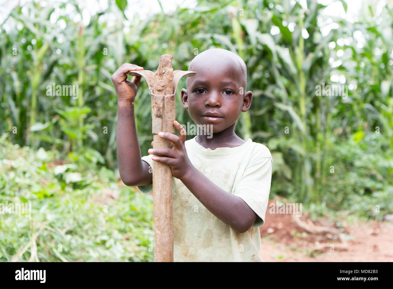 Uganda. 17 June 2017. A little Ugandan boy holding a hoe. Stock Photo