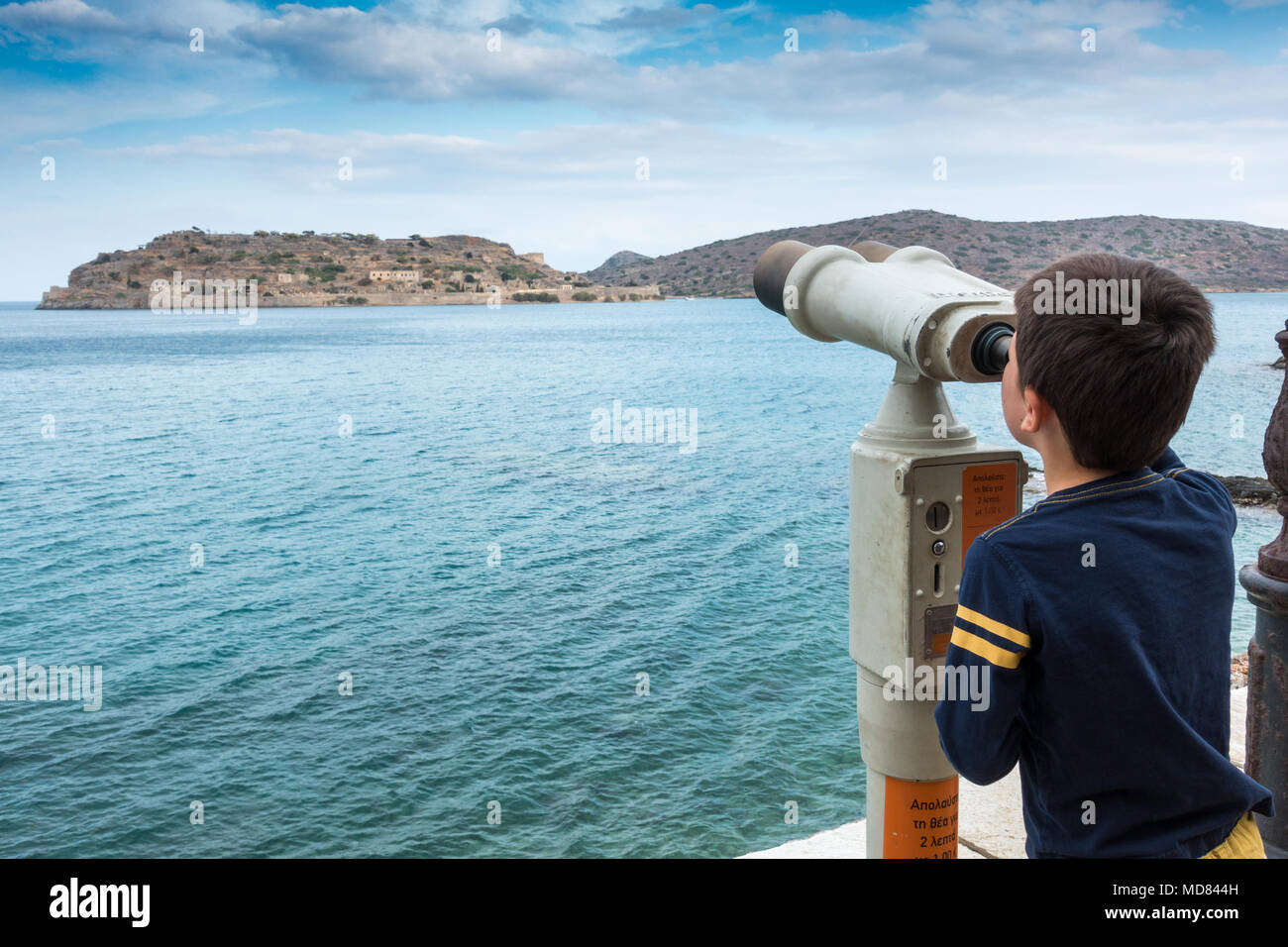 Boy admiring scenic view of sea and mountain through coin operated binoculars Stock Photo