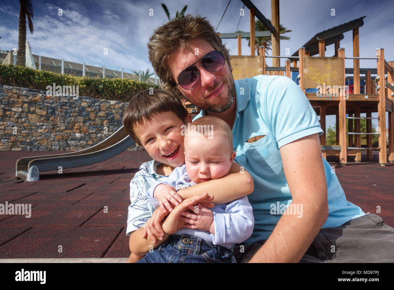 Happy boys with father at playground, Greece Stock Photo