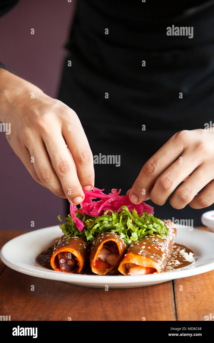 Enchiladas de Cameron y pulp (rolled tortillas stuffed with shrimp and octopus) being garnished by Chef Alan Zamudio at La Mazatleca  Mazatlan, Mexico Stock Photo