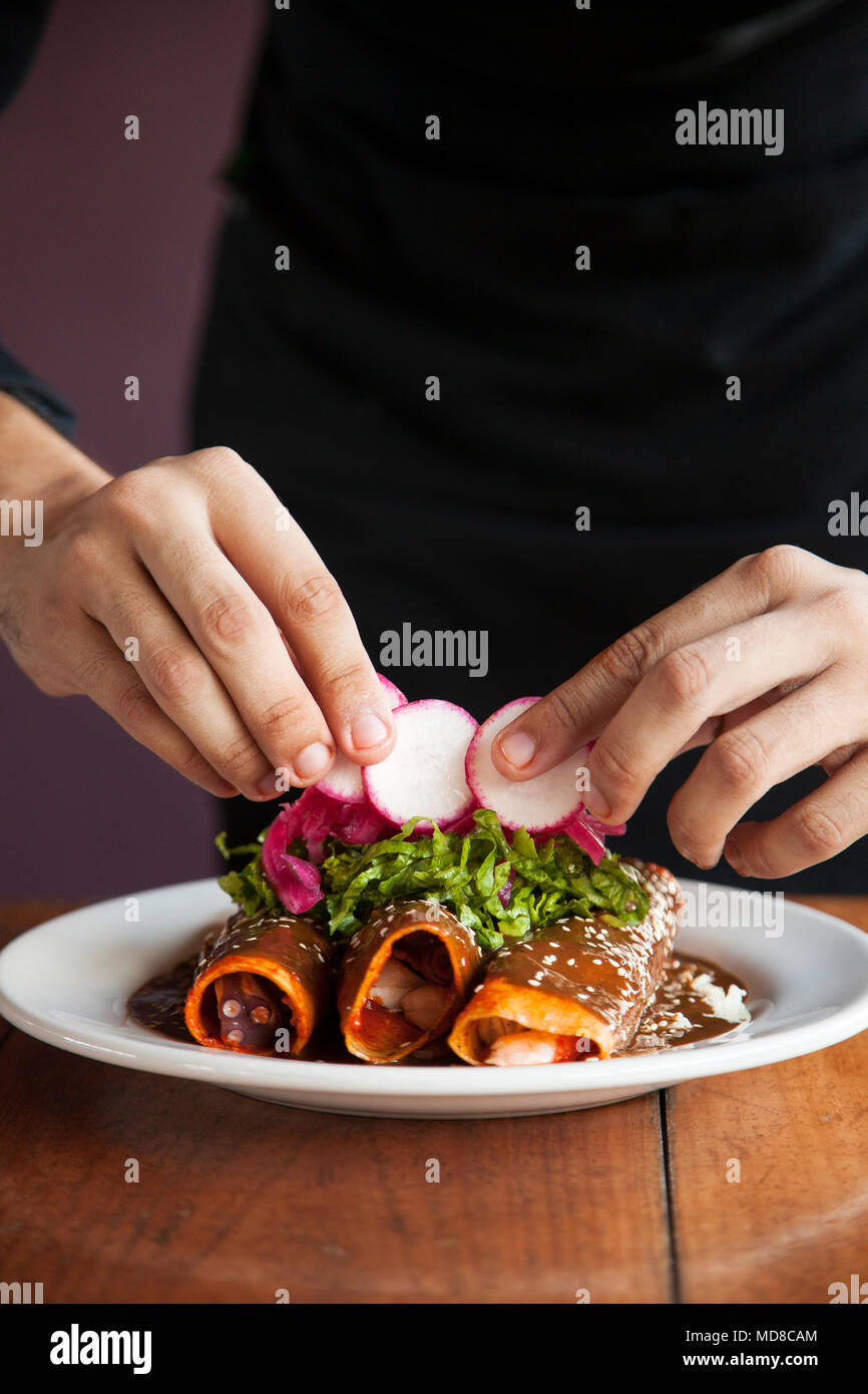 Enchiladas de Cameron y pulp (rolled tortillas stuffed with shrimp and octopus) being garnished by Chef Alan Zamudio at La Mazatleca  Mazatlan, Mexico Stock Photo