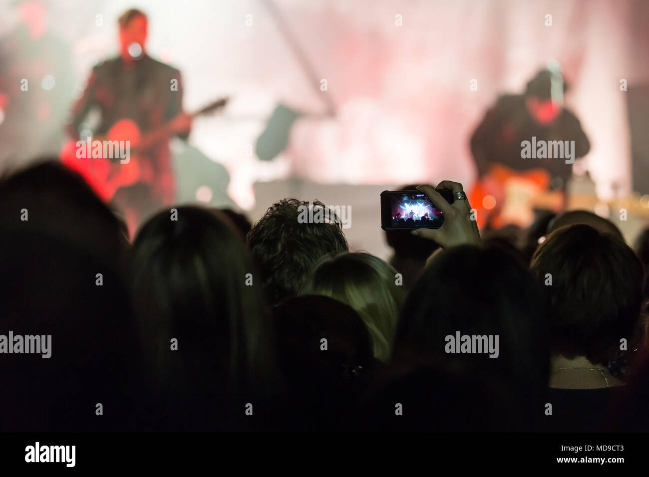 Concertgoer takes a photo with I Phone at the concert of the Swiss band 77 Bombay Street live at Schüür Lucerne, Switzerland Stock Photo