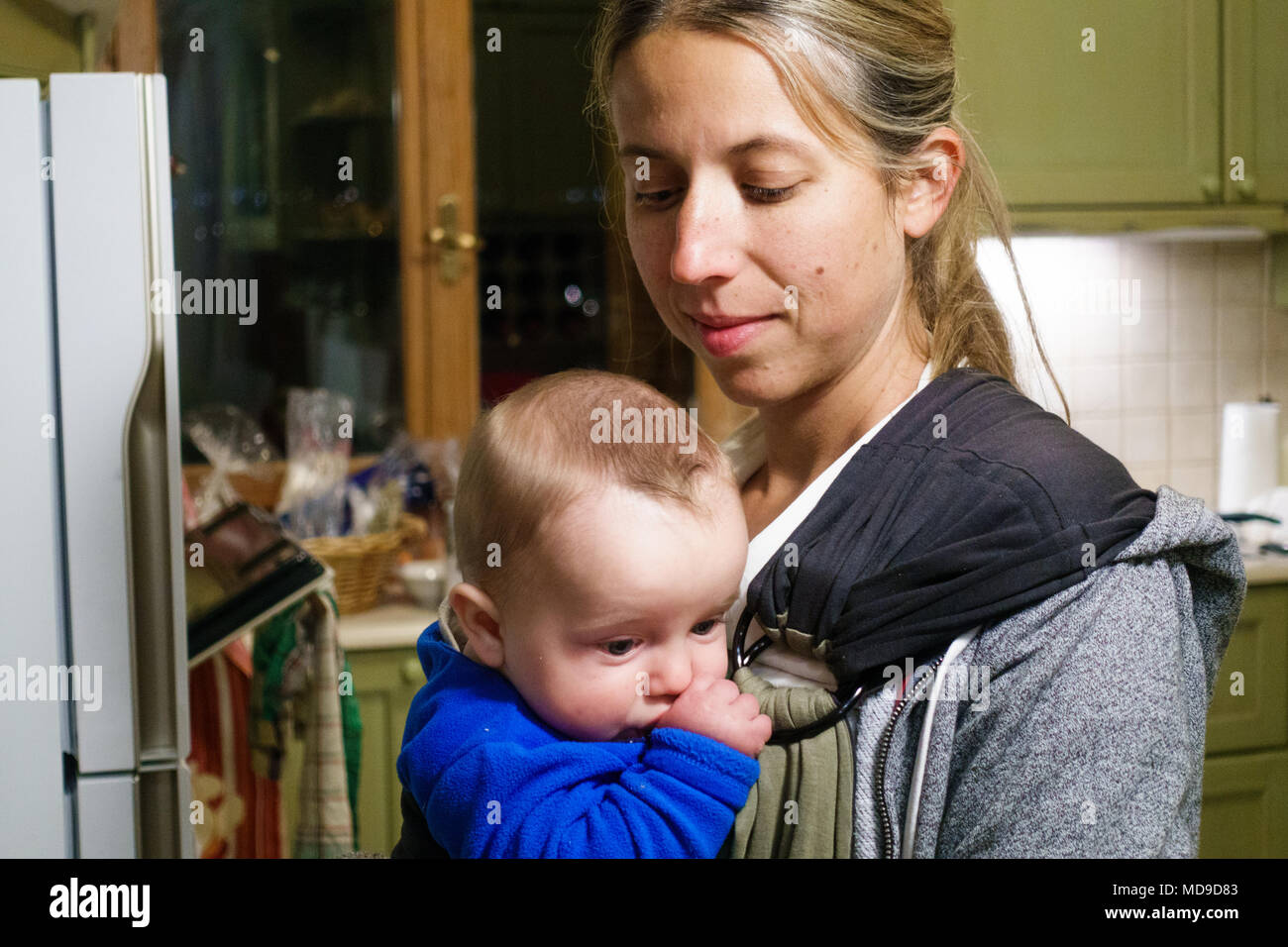 Mother carrying baby boy in kitchen, Greece Stock Photo