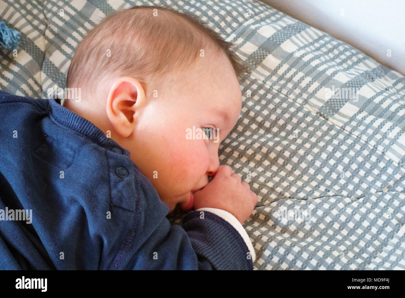 Top view of baby boy thumb sucking in bed, Greece Stock Photo