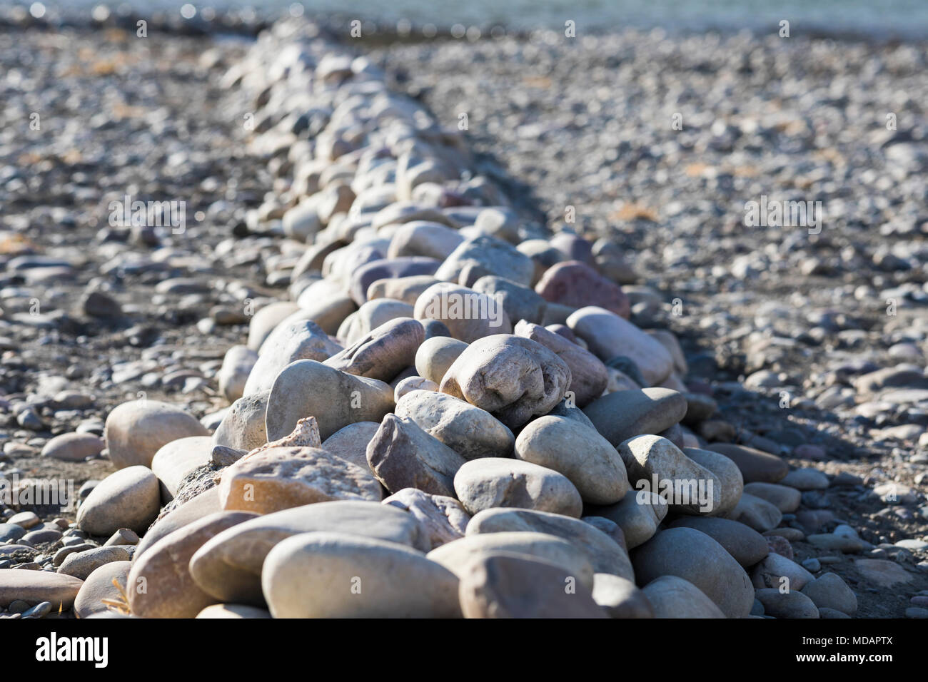 Rocks piled on the river edge in a line on the bank of the Oldman River in Lethbridge, Alberta, Canada Stock Photo