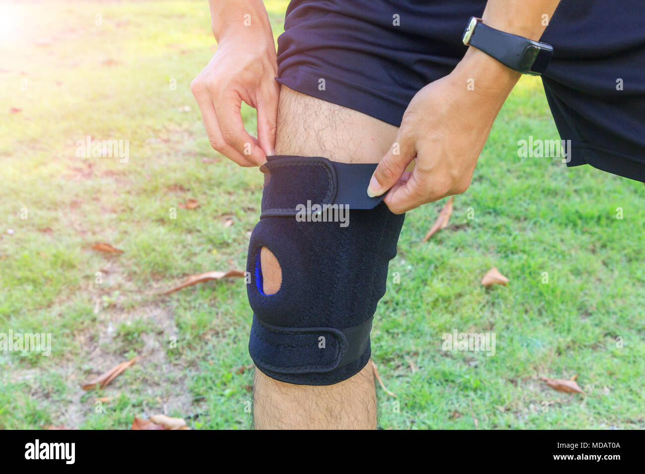 The man wear the Knee Support Brace Patella with sunlight in the park