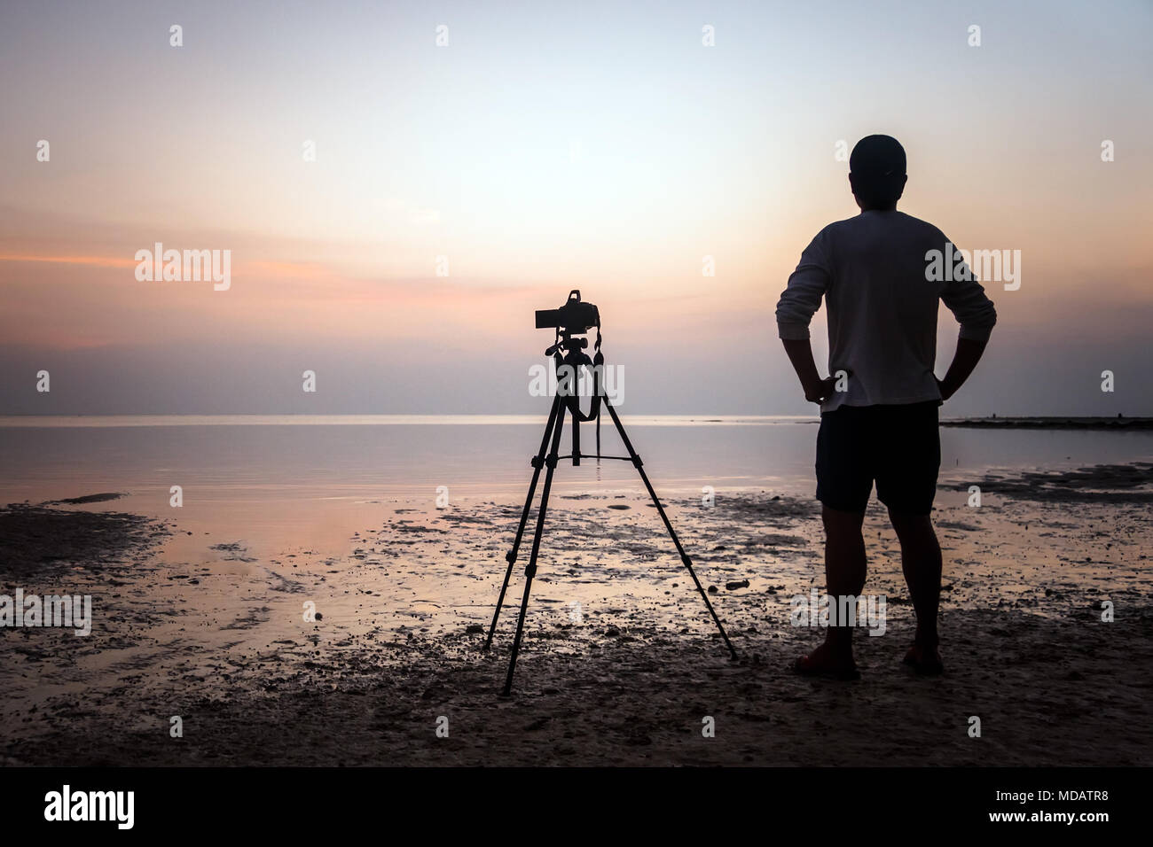 The Photographer takes a good shot on the Huahin beach, Thailand. photographer shoots video of the sunrise in the morning at low tide Stock Photo
