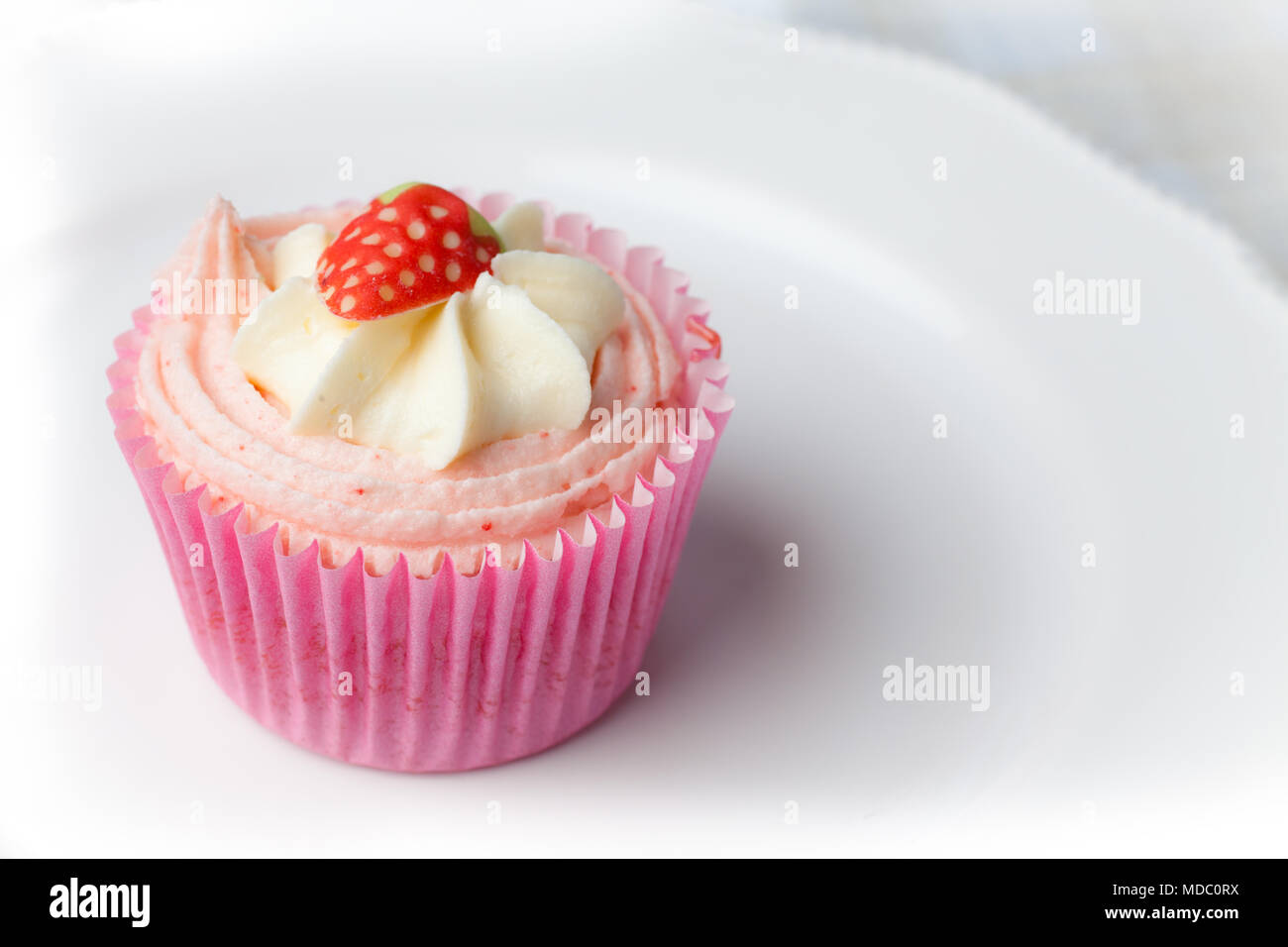 Pink strawberry cupcake on white plate Stock Photo