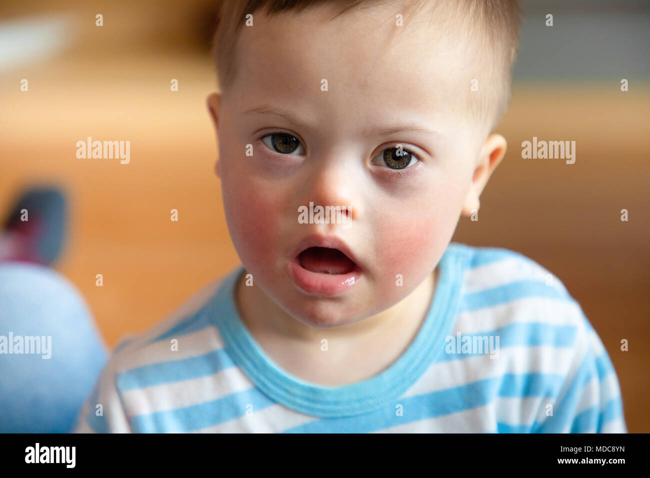Portrait of cute baby boy with Down syndrome in home living room Stock Photo