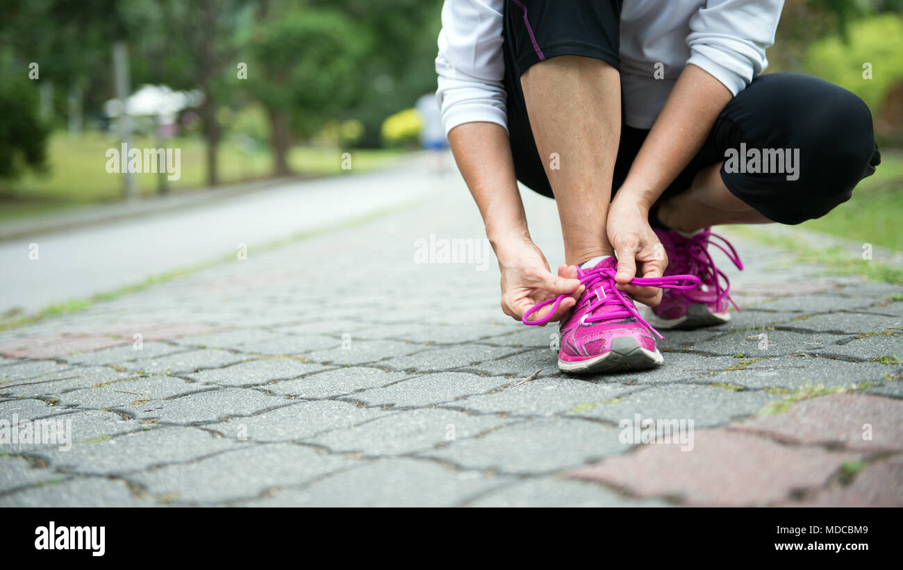 Jogger tighten her running shoe laces Stock Photo