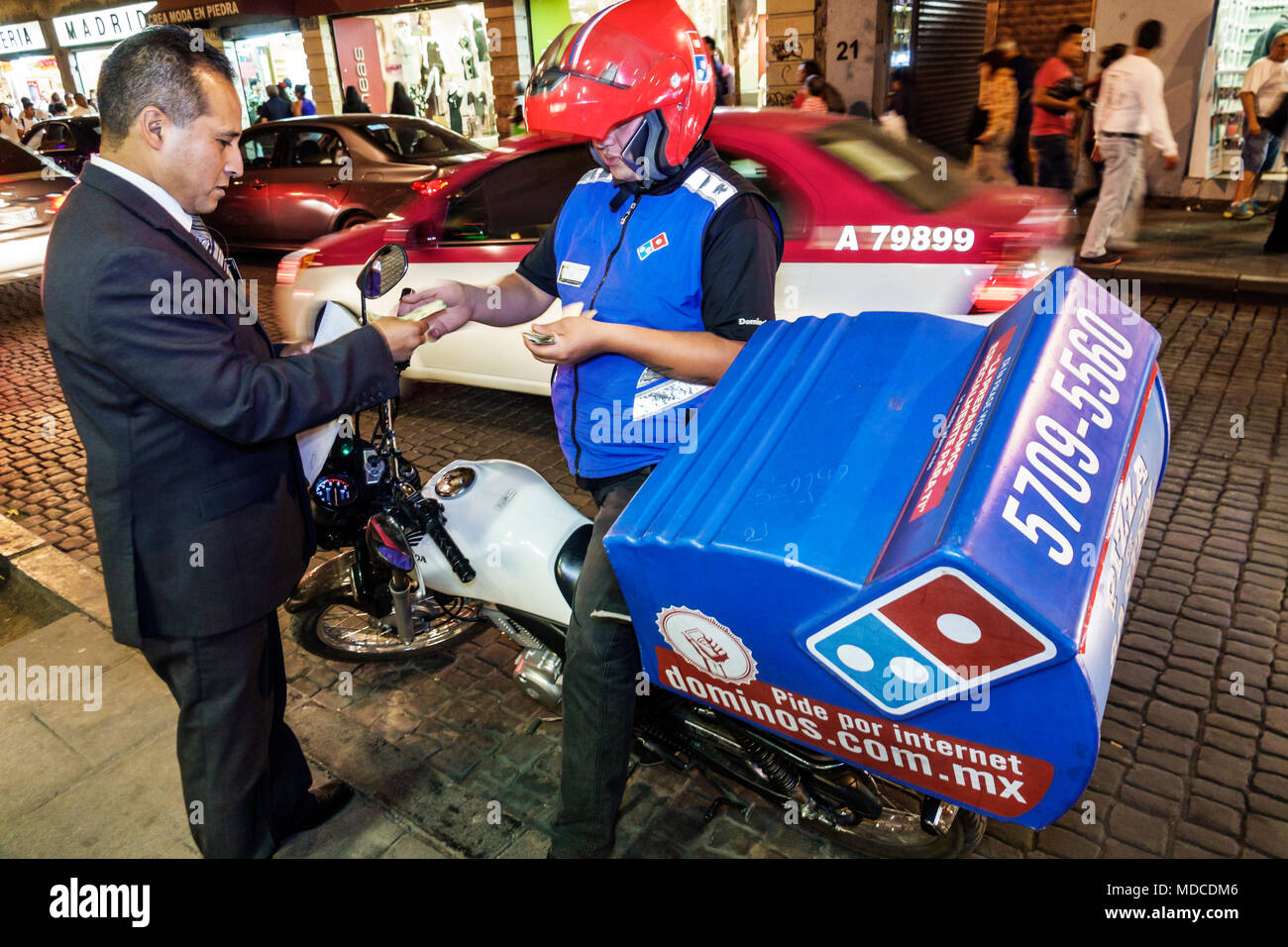 Mexico City,Mexican,Hispanic,historic Center Centre,Calle 5 de Febrero,Dominos,pizza,delivery man,motorcycle,transaction paying pays buying buys,night Stock Photo