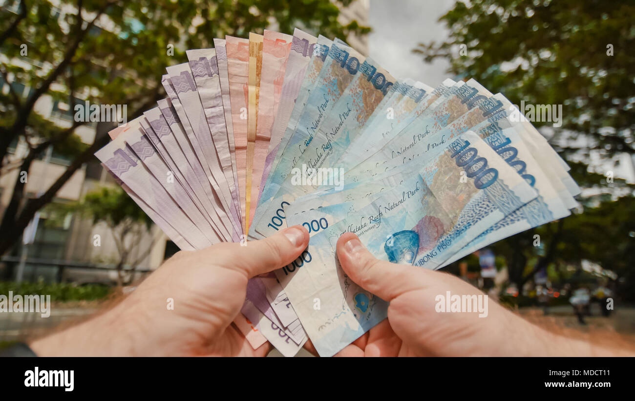 A man holds Philippine money bills in his hands. Stock Photo