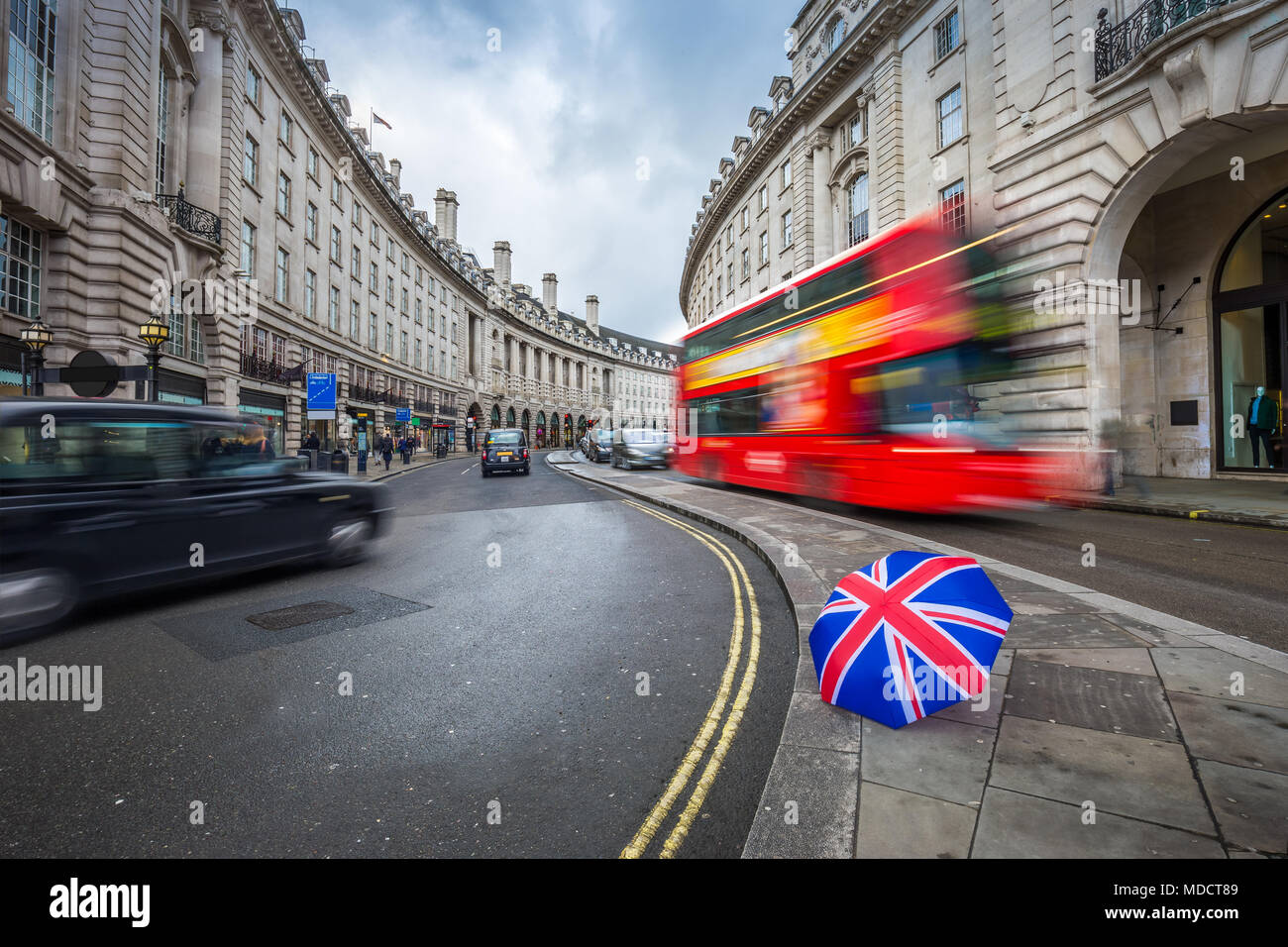 London, England - Iconic red double-decker bus and black taxies on the move on Regent Street with british umbrella Stock Photo