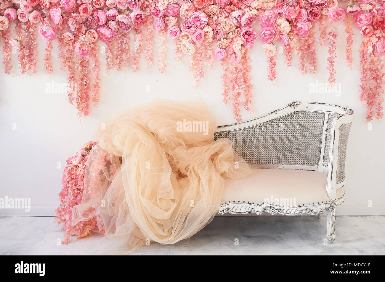 Old carved daybed with soft upholstery against a white wall decorated