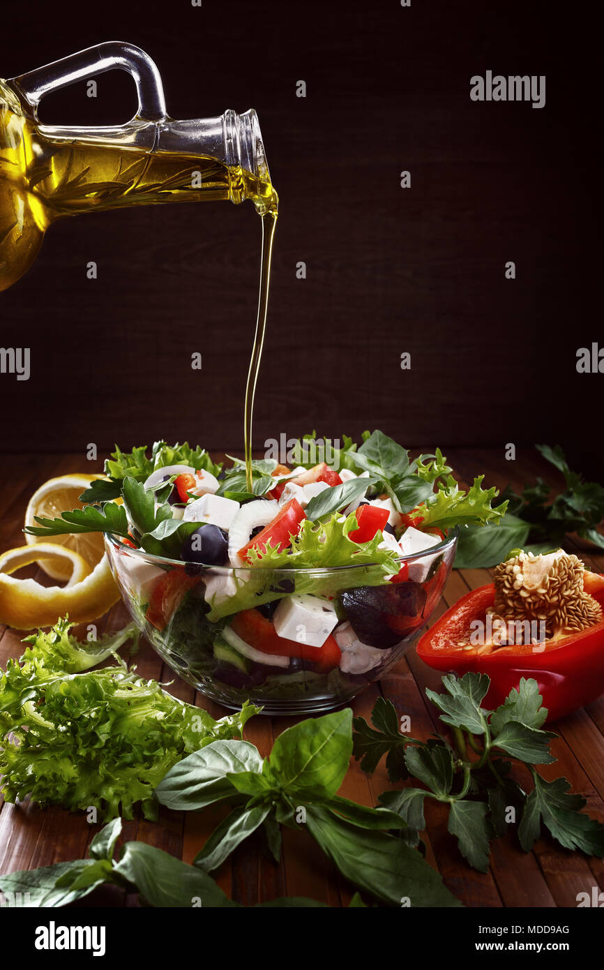 Greek salad with olive oil pouring from a bottle and fresh vegetables. Copy spase. Stock Photo