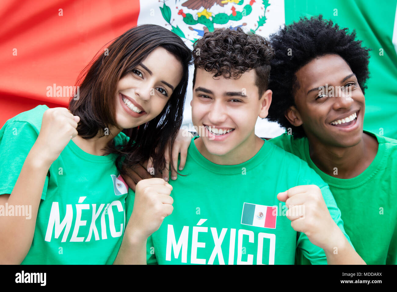 Group of mexican soccer fans with flag of mexico supporting the national team at stadium Stock Photo