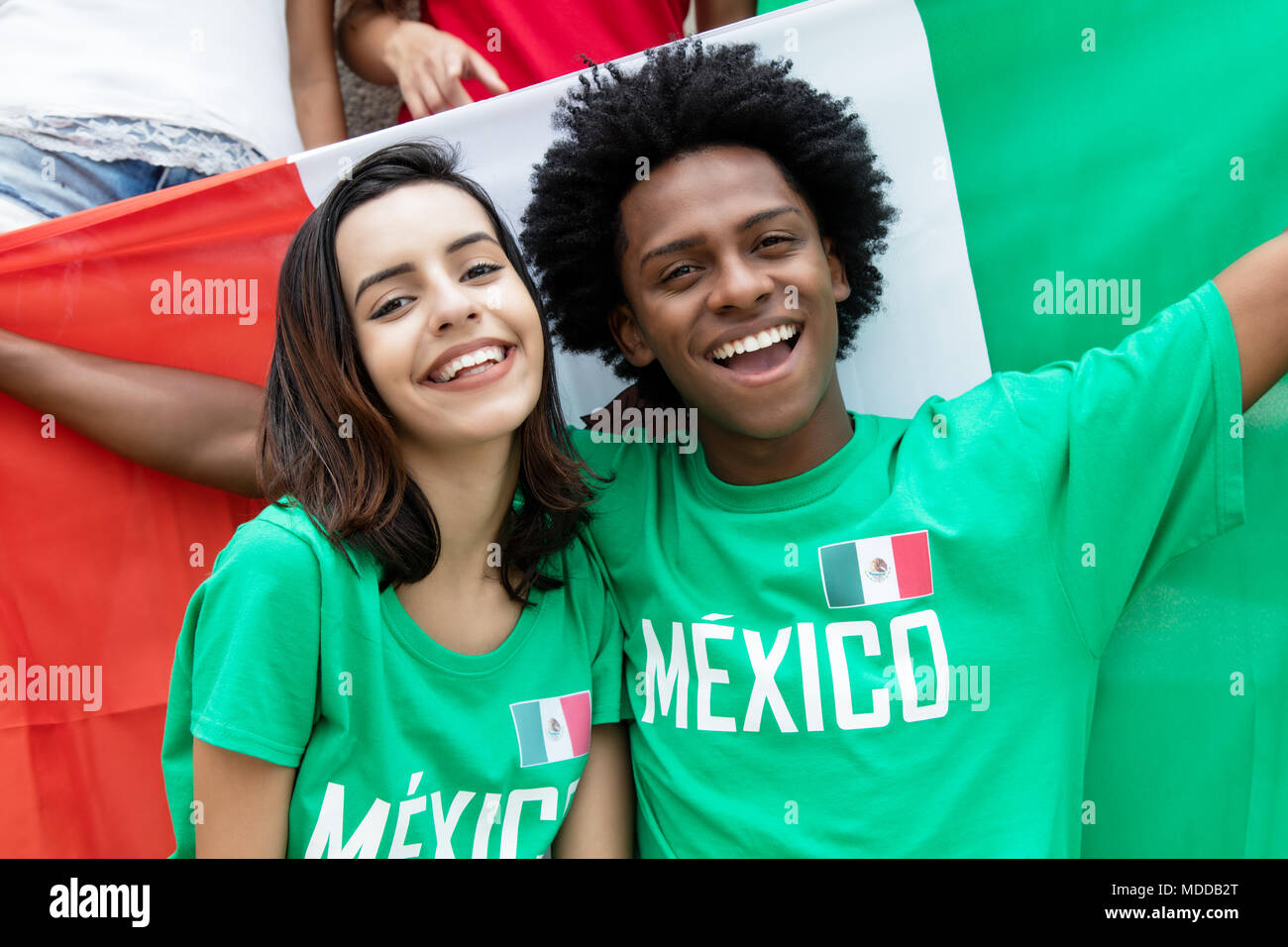 Two cheering mexican soccer fans with flag of mexico supporting the national team at stadium Stock Photo