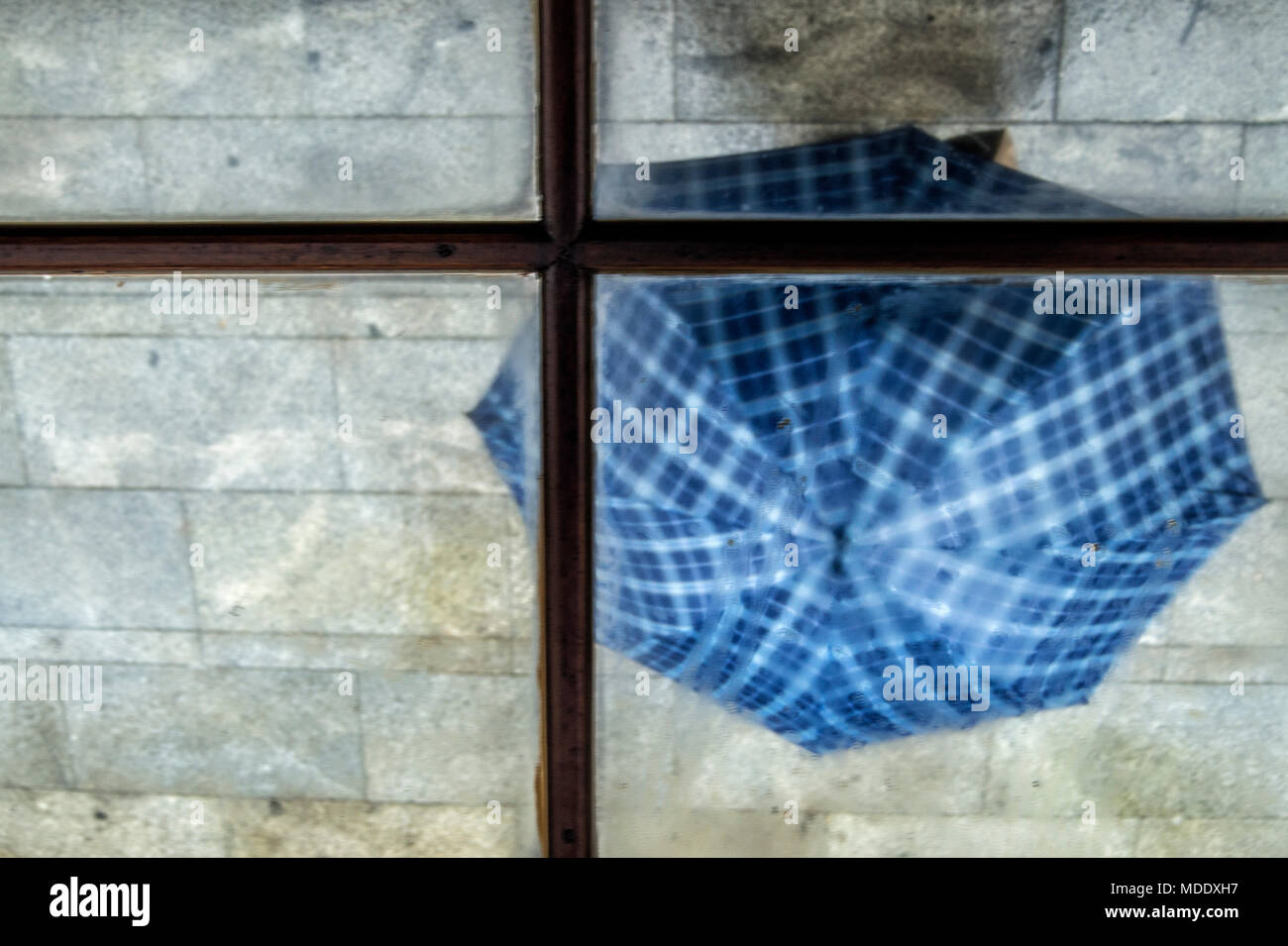 A blue umbrella reflected in the mirror of a building marquee in a place in Madrid. Spain. Stock Photo