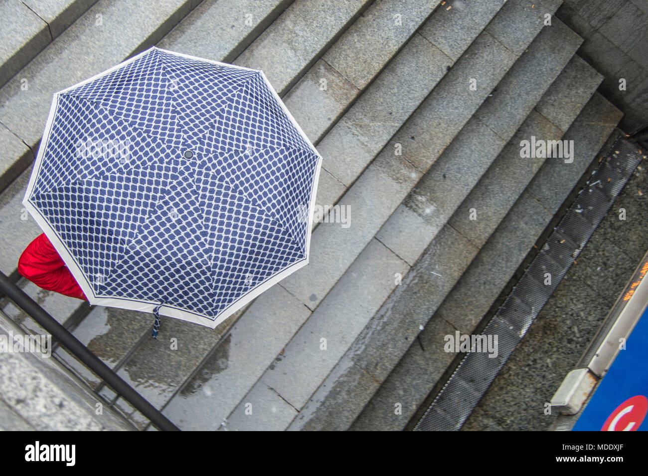 a person covered with an umbrella on a rainy day down the stairs of the Madrid metro. Spain. Stock Photo