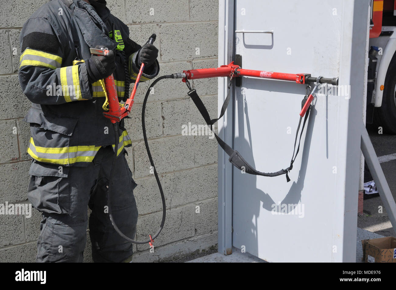Fire fighter uses hydraulic tools to breach a locked door Stock Photo