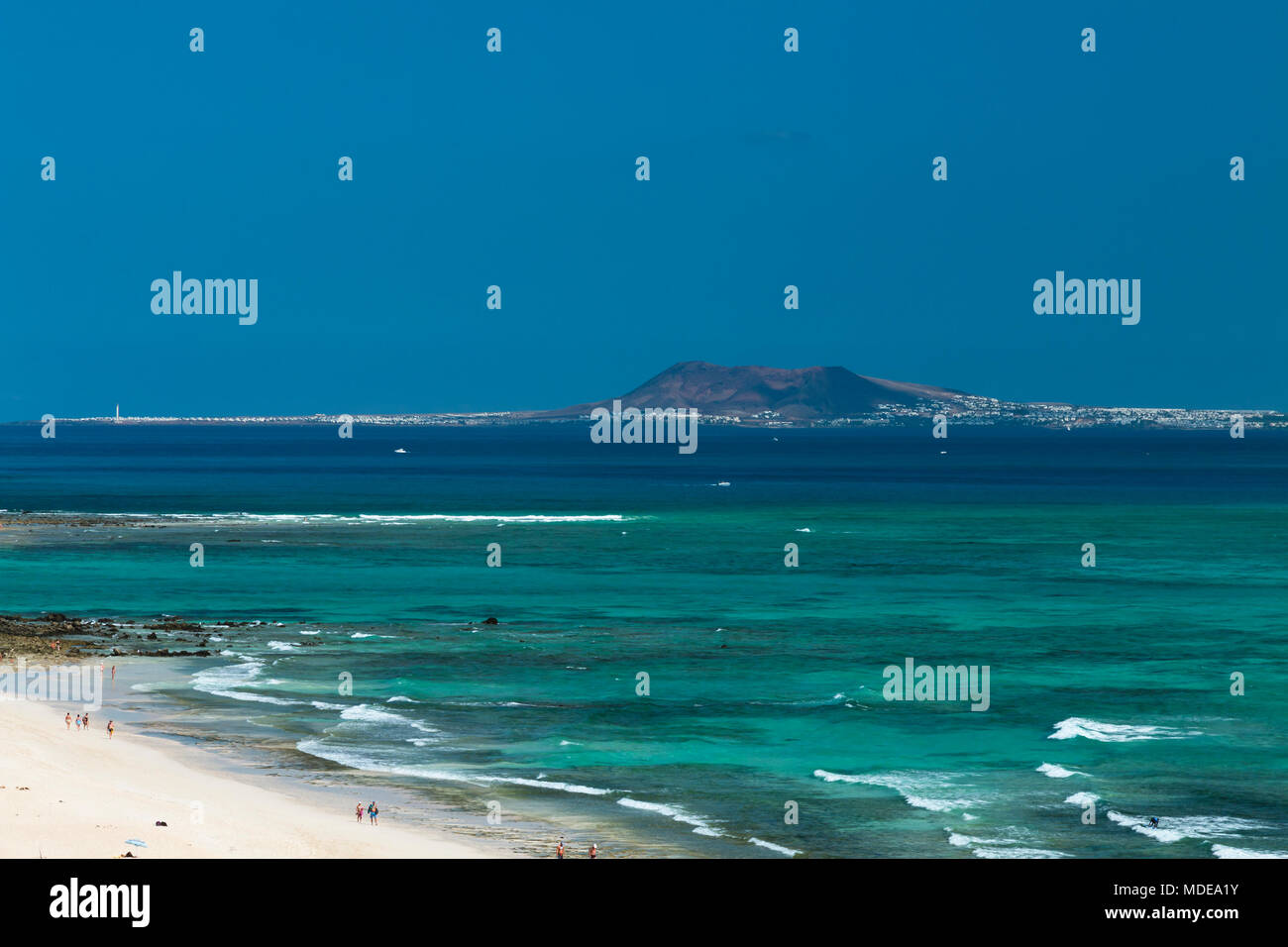 View from Corralejo in Fuerteventura, Spain to Lanzarote with the Montana Roja and the Faro de Pechiguera to the left. Stock Photo