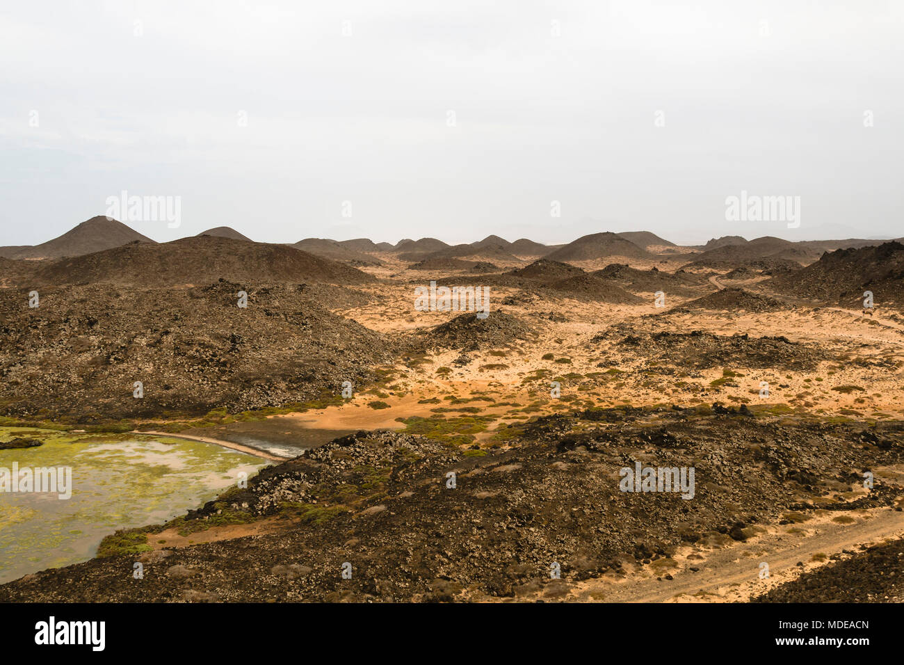 A small brackish water lake on the Isla de Lobos in Fuerteventura, Spain with the typical moon like volcanic landscape of the island. Stock Photo
