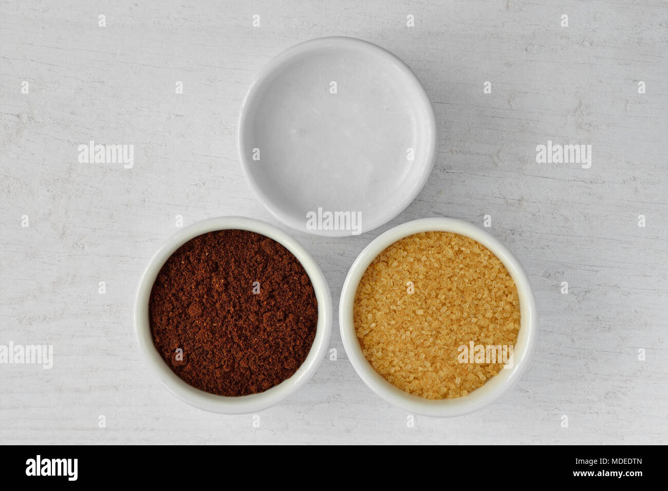 Homemade face scrub made out of coconut oil, coffee powder and brown sugar on wooden background Stock Photo