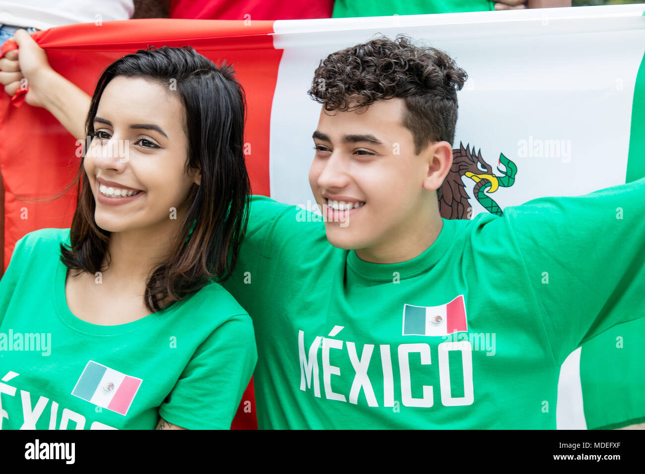 Happy soccer fans from Mexico with mexican flag outdoors at stadium