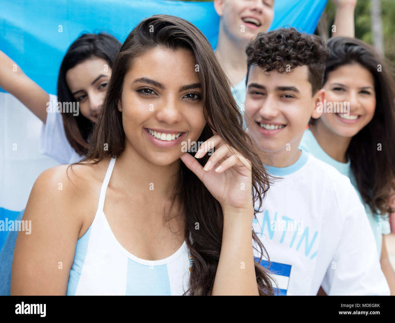 Argentinian woman with other soccer fans and flag of Argentina at stadium Stock Photo