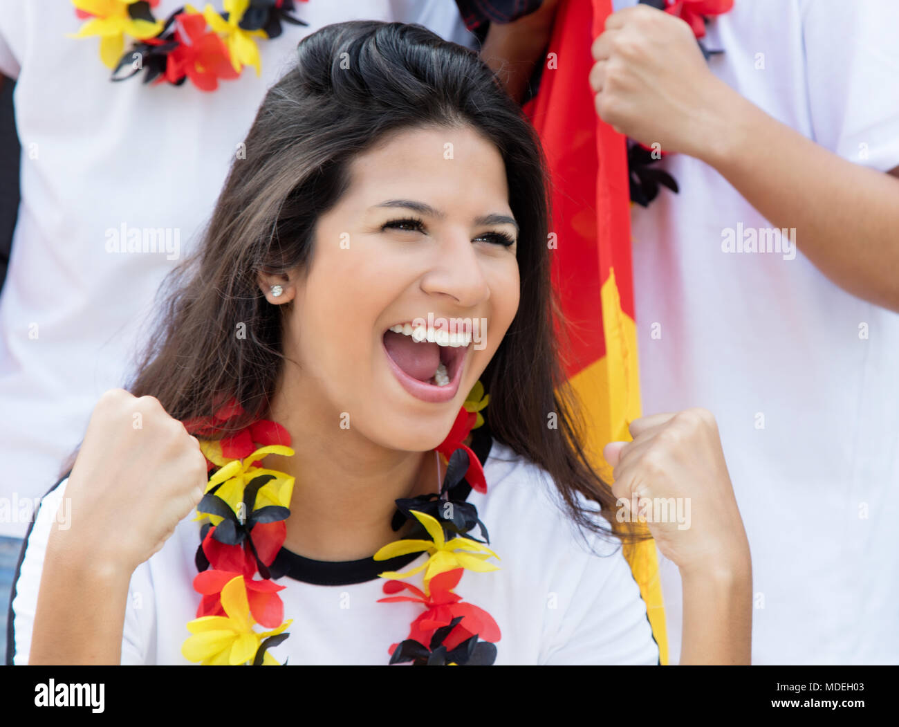 Happy german soccer fan at stadium with other fans and german flag Stock Photo