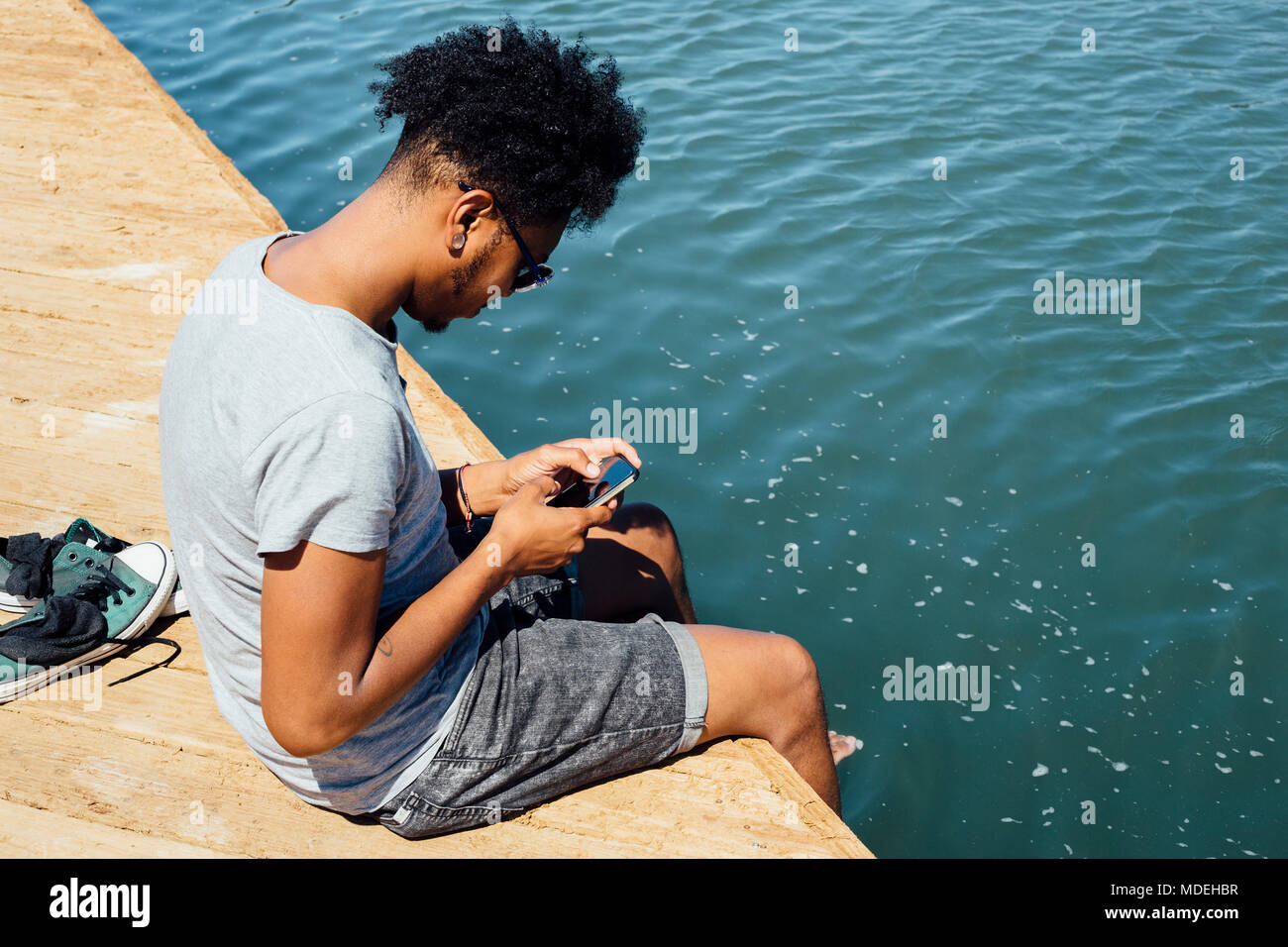 Man using mobile phone by edge of water Stock Photo